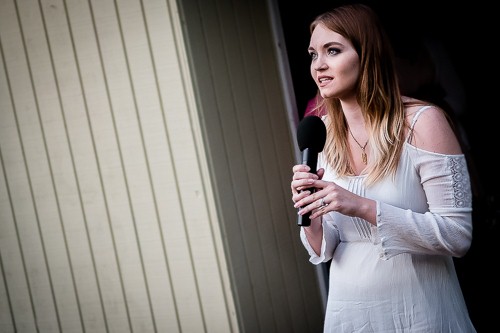 A girl in a white dress singing into a microphone
