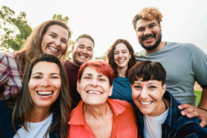 Multiracial friends with different age and ethnicity having fun taking self portrait at park city. Pov of group of people smiling on mobile phone camera