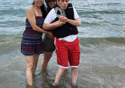 A man with disability and two caregivers at the beach