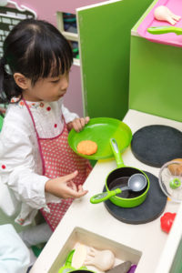 Asian Chinese little girl role-playing at kitchen at indoor playground