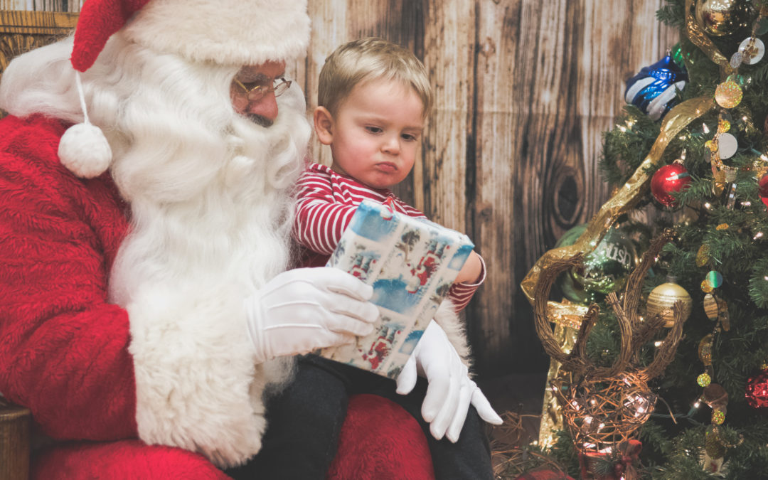 Santa hands a wrapped gift to a toddler boy
