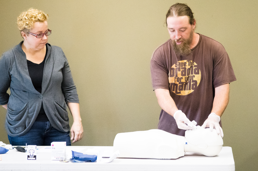 An instructor observes a REVIVE class participant uses a medical dummy to practice giving naloxone to reverse an opioid oversode.