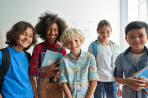 Happy diverse junior school students children group looking at camera standing in classroom.