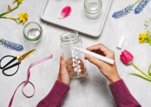 Step 2. Paint a plant motif on a glass jar with white acrylic painter. 