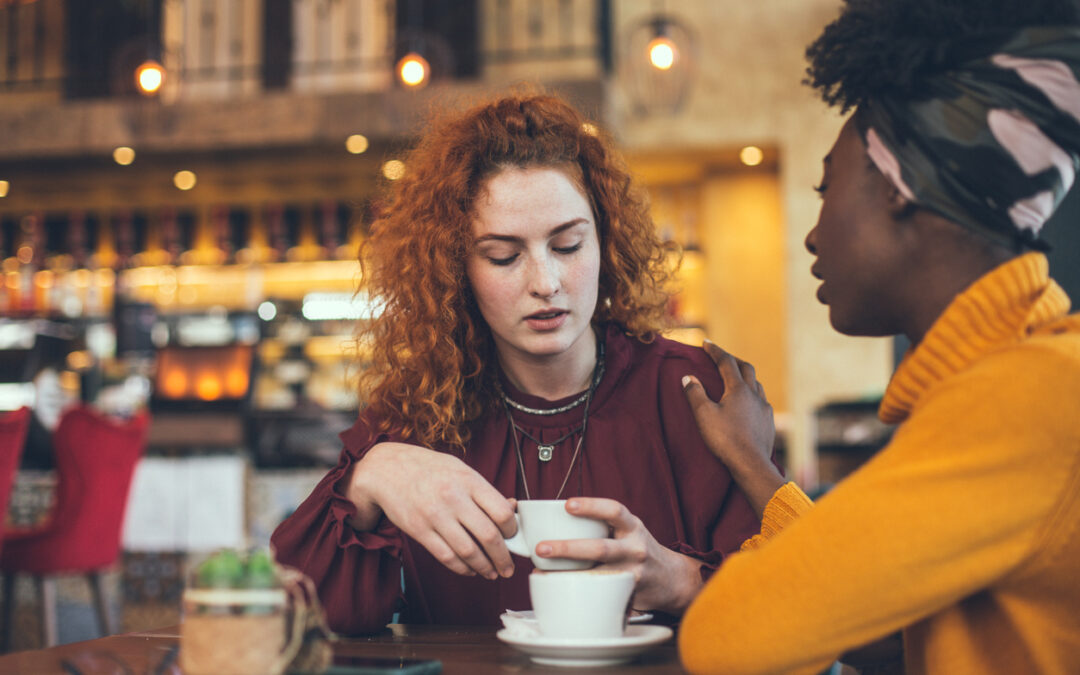 A young woman is talking with a female friend about her problem in a cafe.