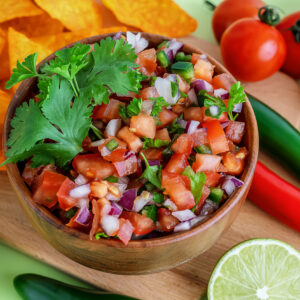 Close up of salsa Roja traditional Mexican sauce with ingredients for making on a light green background. homemade recipe Pico de Gallo with nachos.