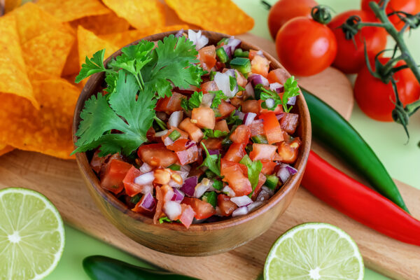 Close up of salsa Roja traditional Mexican sauce with ingredients for making on a light green background. homemade recipe Pico de Gallo with nachos.