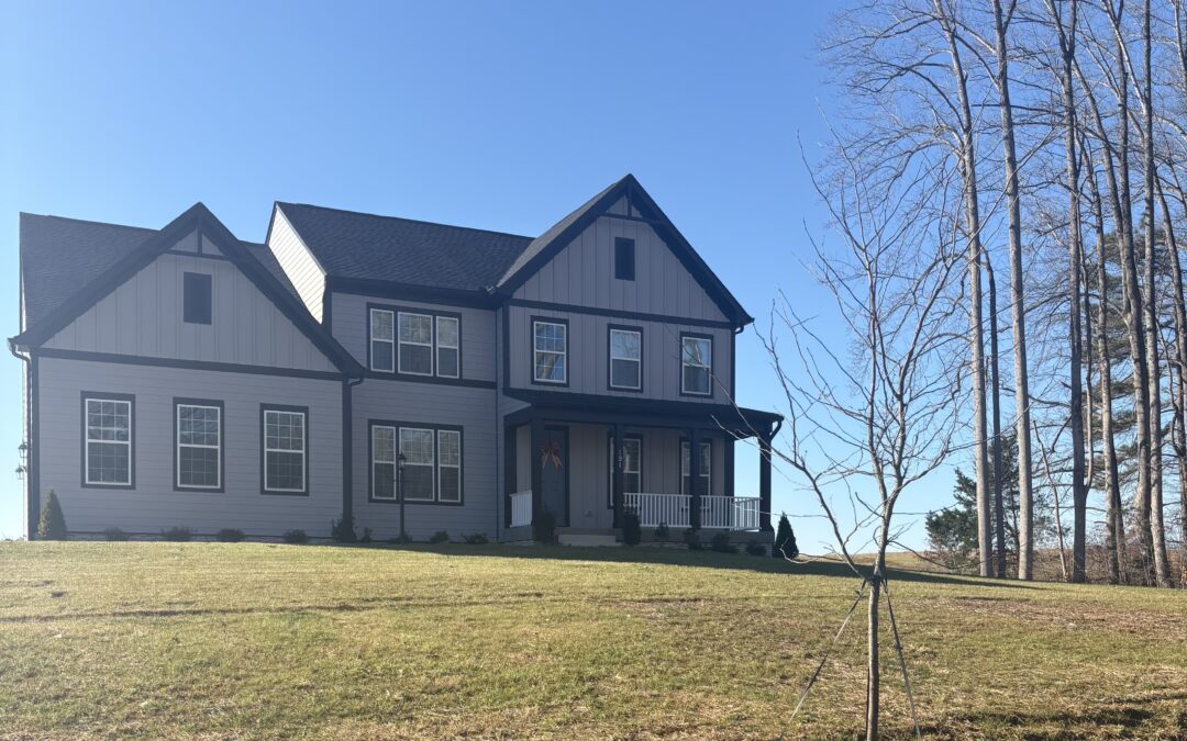 A gray two-story home on a large, grassy lot