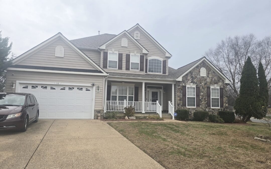 A tan two-story home on a large, grassy lot