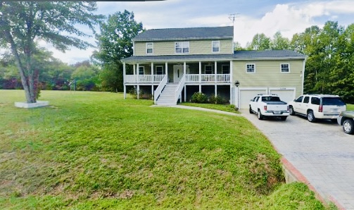 A yellow two-story home on a large, grassy lot