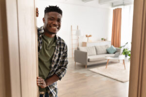 African American young man smiles as he opens the door to an apartment