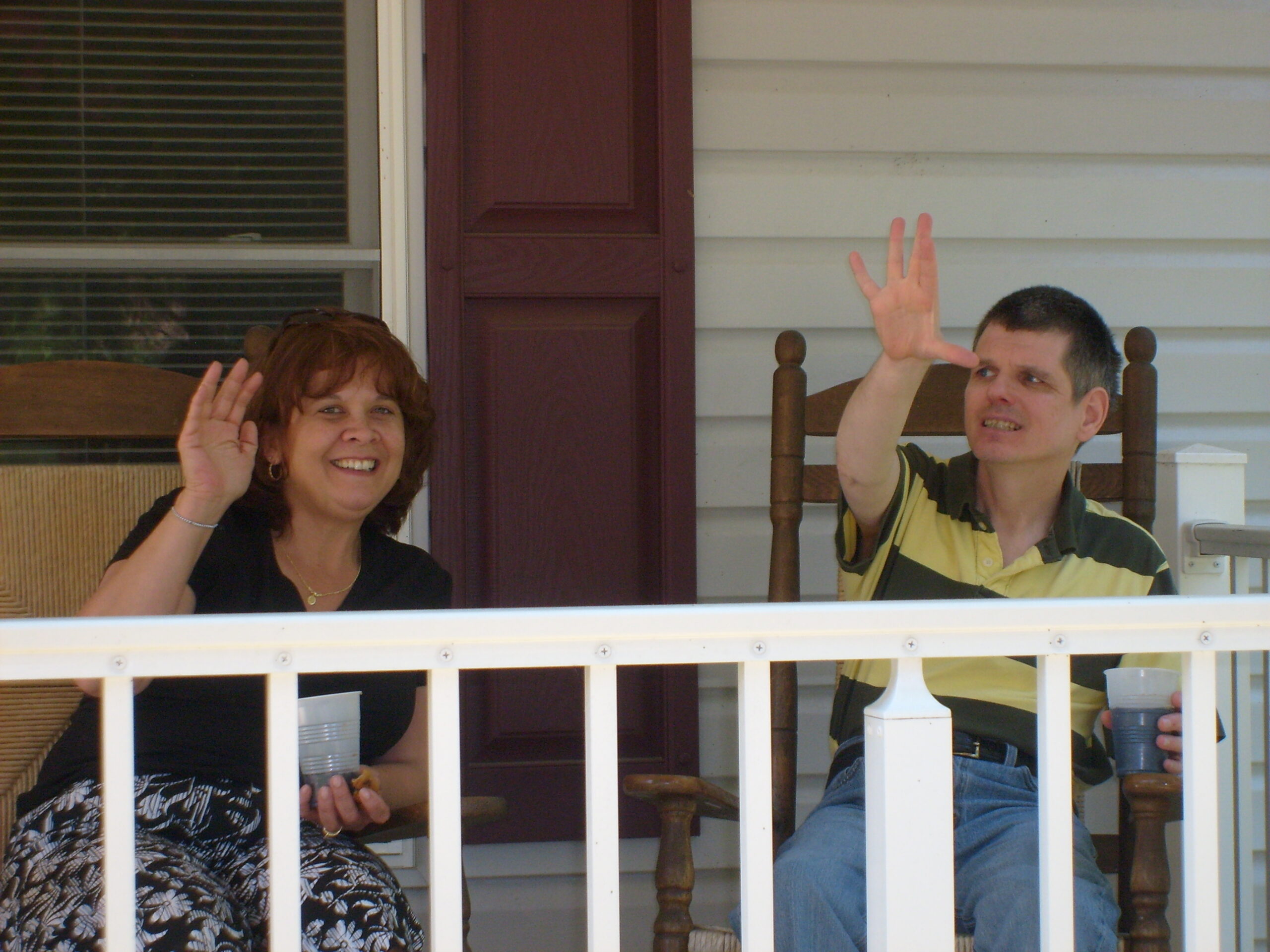 A man and a woman wave from a front porch